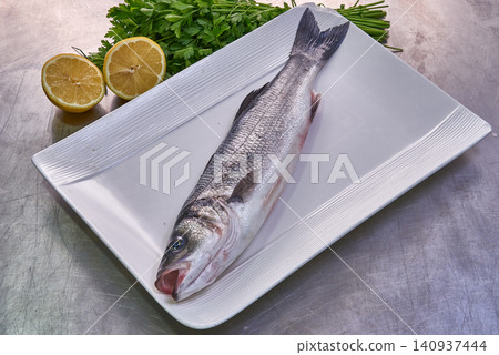 sea bass on a white plate with parsley and lemon sea bass on a white plate with parsley and lemon 140937444