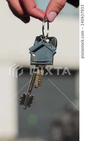 Vertical video Close-up of house key in the hand of woman house against the background. Real estate concept for buying a new home. Vertical video Close-up of house key in the hand of woman house against the background. Real estate concept for buying a new home. 140937933