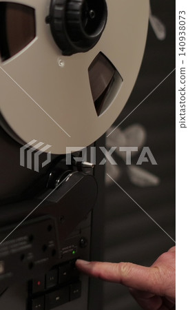 Vertical video Man hand turns on music on reel to reel tape recorder playing. Rotating vintage music player close up. Vertical video Man hand turns on music on reel to reel tape recorder playing. Rotating vintage music player close up. 140938073
