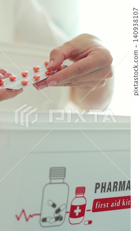 Vertical video Woman takes out blister of pills from first aid kit at home. Vertical video Woman takes out blister of pills from first aid kit at home. 140938107