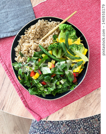 Quinoa bowl features boiled eggs, green beans, and broccoli. A fresh salad sits nearby. A cup of coffee completes the healthy breakfast setting Quinoa bowl features boiled eggs, green beans, and broccoli. A fresh salad sits nearby. A cup of coffee completes the healthy breakfast setting 140938179