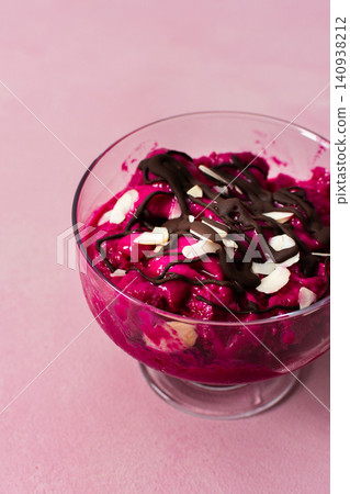 Two bowls of healthy ice cream sit on a table. The ice cream features strawberries, bananas, beets, and Greek yogurt. Chocolate and nuts top the creamy dessert. Spoons are beside the bowls Two bowls of healthy ice cream sit on a table. The ice cream features strawberries, bananas, beets, and Greek yogurt. Chocolate and nuts top the creamy dessert. Spoons are beside the bowls 140938212