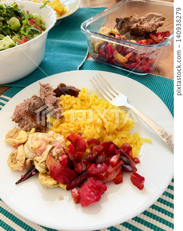 A plate holds turmeric rice, pieces of baked turkey, freshly prepared salad, and baked vegetables. The meal is colorful and inviting, perfect for breakfast or lunch A plate holds turmeric rice, pieces of baked turkey, freshly prepared salad, and baked vegetables. The meal is colorful and inviting, perfect for breakfast or lunch 140938279