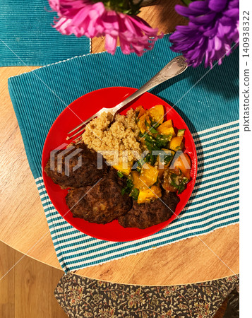 A red plate holds liver pancakes, quinoa, and fresh salad. The meal is arranged neatly on a table with a blue tablecloth and flowers, perfect for a healthy breakfast or lunch A red plate holds liver pancakes, quinoa, and fresh salad. The meal is arranged neatly on a table with a blue tablecloth and flowers, perfect for a healthy breakfast or lunch 140938322