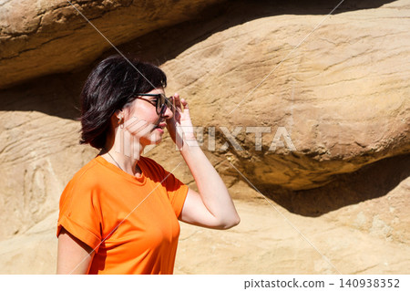 Young woman in a short summer orange dress and sunglasses enjoying a sunny day outdoors, radiating joy and vibrant summer vibes Young woman in a short summer orange dress and sunglasses enjoying a sunny day outdoors, radiating joy and vibrant summer vibes 140938352