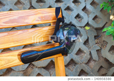 Abandoned snorkeling mask hanging on a bench, a forgotten treasure left behind by its owner, capturing the essence of summer adventures and ocean exploration Abandoned snorkeling mask hanging on a bench, a forgotten treasure left behind by its owner, capturing the essence of summer adventures and ocean exploration 140938380