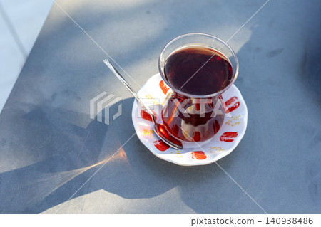 Close-up of traditional Turkish tea in a clear tulip glass on a wooden table Close-up of traditional Turkish tea in a clear tulip glass on a wooden table 140938486