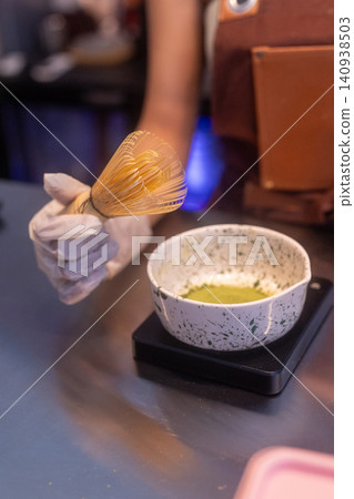 Close-up of a barista preparing a fresh matcha green tea latte in a cafe 140938503
