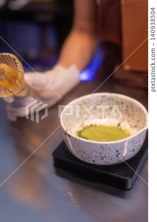 Close-up of a barista preparing a fresh matcha green tea latte in a cafe Close-up of a barista preparing a fresh matcha green tea latte in a cafe 140938504