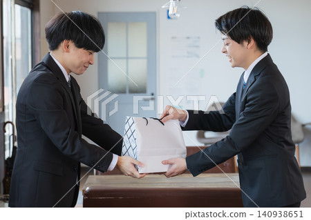 一位男商人遞過一個紙袋。 一位男商人遞過一個紙袋。 140938651