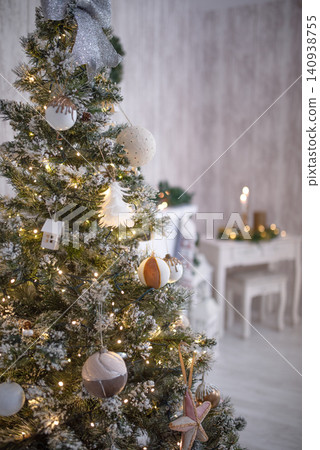 Christmas tree adorned with festive ornaments, twinkling lights, and a silver bow, creating a warm and inviting holiday atmosphere in a cozy interior setting Christmas tree adorned with festive ornaments, twinkling lights, and a silver bow, creating a warm and inviting holiday atmosphere in a cozy interior setting 140938755