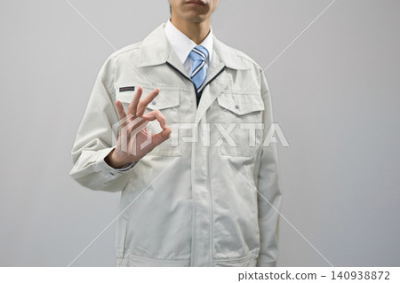 A young man in work clothes makes an OK sign. A young man in work clothes makes an OK sign. 140938872