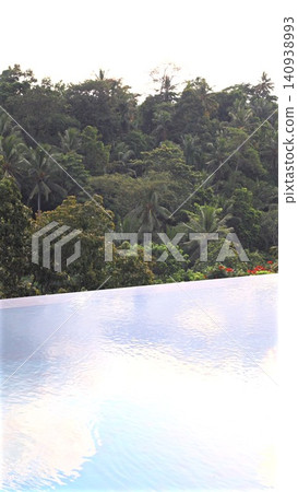 Infinity pool overlooking dense tropical forest canopy at sunrise, calm reflective water in foreground and lush palms beyond, serene luxury resort landscape, with pool, infinity, water, reflection Infinity pool overlooking dense tropical forest canopy at sunrise, calm reflective water in foreground and lush palms beyond, serene luxury resort landscape, with pool, infinity, water, reflection 140938993