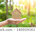 Hands holding a miniature model of a house against a blurred background 140939161