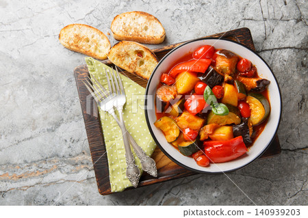 Rustic Ciambotta Vegetable Stew with Zucchini Eggplant Bell Peppers Potatoes Fresh Basil and Tomato Sauce closeup on the plate. Horizontal top view Rustic Ciambotta Vegetable Stew with Zucchini Eggplant Bell Peppers Potatoes Fresh Basil and Tomato Sauce closeup on the plate. Horizontal top view 140939203