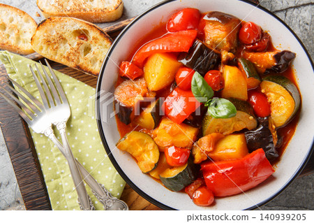 Ciambotta Italian vegetable stew with potatoes, eggplants, tomatoes and peppers closeup on the plate. Horizontal top view 140939205
