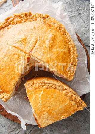 Pizzagaina is a rustic Italian Easter pie stuffed with salami, ham, ricotta and mozzarella cheese closeup on the wooden board. Vertical top view Pizzagaina is a rustic Italian Easter pie stuffed with salami, ham, ricotta and mozzarella cheese closeup on the wooden board. Vertical top view 140939217