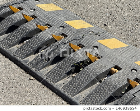 Speed bump with embedded retractable metal spikes on rough concrete road surface background Speed bump with embedded retractable metal spikes on rough concrete road surface background 140939654