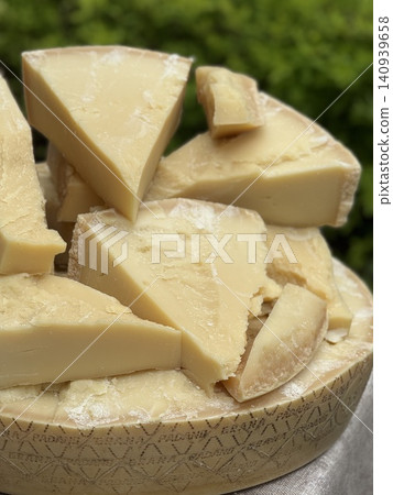 Chunks of Parmesan cheese on a wheel with a blurred natural background Chunks of Parmesan cheese on a wheel with a blurred natural background 140939658