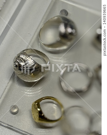 Jewelry rings displayed on a transparent tray, showcasing metallic design variety Jewelry rings displayed on a transparent tray, showcasing metallic design variety 140939665