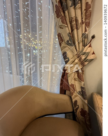Curtains with floral patterns and fairy lights in cozy decorated living room, perfect for a background Curtains with floral patterns and fairy lights in cozy decorated living room, perfect for a background 140939672