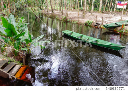small wooden canoe on dark stream in the middle of Brazilian Amazon rainforest small wooden canoe on dark stream in the middle of Brazilian Amazon rainforest 140939771