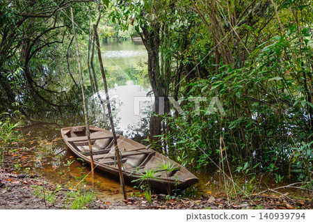 small wooden canoe on riverbank in the middle of Brazilian Amazon rainforest small wooden canoe on riverbank in the middle of Brazilian Amazon rainforest 140939794