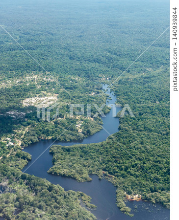 Aerial view over dark river cutting through flooded Amazon rainforest. Amazonas, Brazil 140939844