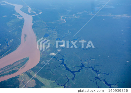 Aerial view over immense Amazon rainforest with a muddy river cutting through forest. Amazonas, Brazil 140939856