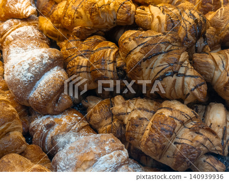 A stack of fresh croissants with chocolate drizzle and powdered sugar for a gourmet breakfast in a bakery, illustrating artisanal pastry quality and classic French culinary style A stack of fresh croissants with chocolate drizzle and powdered sugar for a gourmet breakfast in a bakery, illustrating artisanal pastry quality and classic French culinary style 140939936