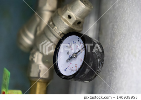 Industrial pressure gauge attached to metallic pipes shows system status in a heating unit, providing monitoring and diagnostic data for building maintenance and engineering operations Industrial pressure gauge attached to metallic pipes shows system status in a heating unit, providing monitoring and diagnostic data for building maintenance and engineering operations 140939953