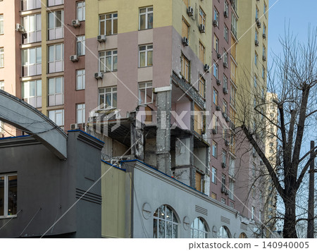 Damaged apartment building facade showing structural destruction from a blast, highlighting the impact of urban warfare on civilian infrastructure and human living in crisis zones 140940005