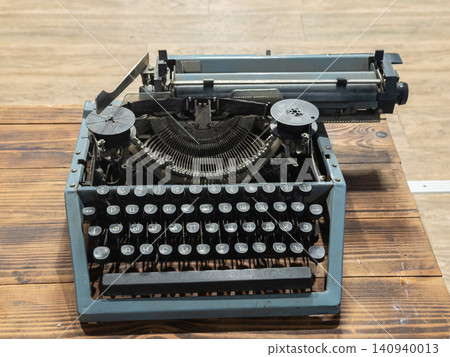 A vintage grey typewriter sits on a rustic wooden desk, serving as a classic creative writing tool that evokes nostalgic charm and traditional journalism in an old study room A vintage grey typewriter sits on a rustic wooden desk, serving as a classic creative writing tool that evokes nostalgic charm and traditional journalism in an old study room 140940013