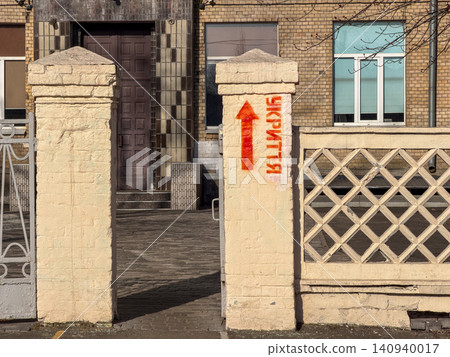 Orange arrow painted on a brick pillar pointing toward a building entrance to indicate a shelter, reflecting emergency preparation measures in a public space during a crisis period 140940017