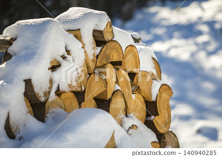 Neatly piled stack of chopped dry trunks wood covered with snow outdoors on bright cold winter sunny day, abstract background, Fire wood logs prepared for winter, ready for burning. Neatly piled stack of chopped dry trunks wood covered with snow outdoors on bright cold winter sunny day, abstract background, Fire wood logs prepared for winter, ready for burning. 140940285