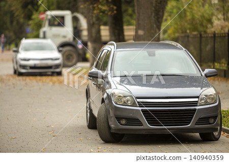 Gray shiny car parked in quiet area on asphalt road on blurred bokeh background on bright sunny day. Transportation and parking concept. Gray shiny car parked in quiet area on asphalt road on blurred bokeh background on bright sunny day. Transportation and parking concept. 140940359