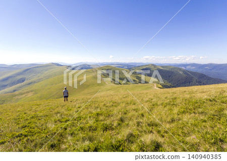 Lonely hiker standing in mountains. Tourist man enjoy mountain view Lonely hiker standing in mountains. Tourist man enjoy mountain view 140940385