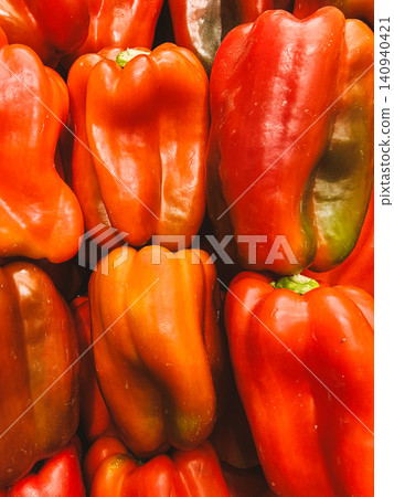 Closeup of stacked red bell peppers with glossy skin and vibrant color filling frame Closeup of stacked red bell peppers with glossy skin and vibrant color filling frame 140940421