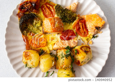 Baked potatoes are served with salmon, broccoli, and tomatoes on a plate. This meal is a good option for breakfast or lunch, offering a balance of nutrition and taste Baked potatoes are served with salmon, broccoli, and tomatoes on a plate. This meal is a good option for breakfast or lunch, offering a balance of nutrition and taste 140940952