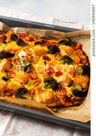 Salmon is baked along with broccoli, tomatoes, and eggs on a deck. This meal is set up for a healthy breakfast or lunch. The food looks fresh and ready to eat 140940987