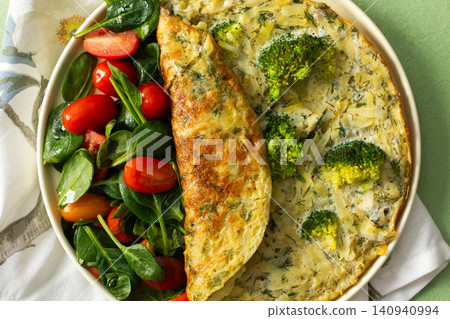 A plate holds a potato omelette made with eggs and filled with spinach and tomatoes. The meal looks fresh and healthy and is ideal for breakfast any day A plate holds a potato omelette made with eggs and filled with spinach and tomatoes. The meal looks fresh and healthy and is ideal for breakfast any day 140940994