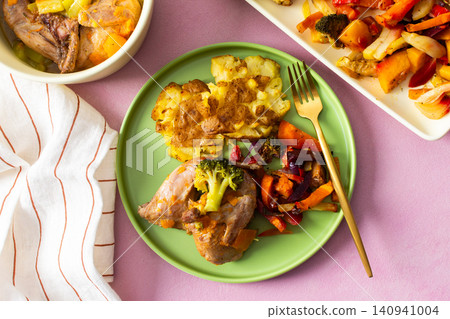Mashed potatoes sit beside baked vegetables and stewed quail on green plates. A light table setting with gold utensils invites a satisfying meal Mashed potatoes sit beside baked vegetables and stewed quail on green plates. A light table setting with gold utensils invites a satisfying meal 140941004