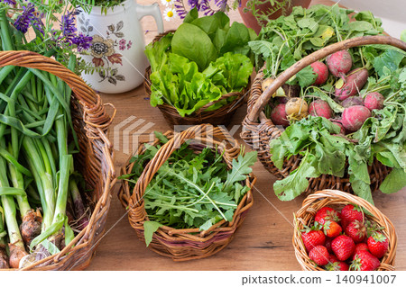 Baskets filled with fresh organic vegetables are placed on a wooden floor. Radishes, green onions, arugula, and lettuce create a colorful display of local produce Baskets filled with fresh organic vegetables are placed on a wooden floor. Radishes, green onions, arugula, and lettuce create a colorful display of local produce 140941007