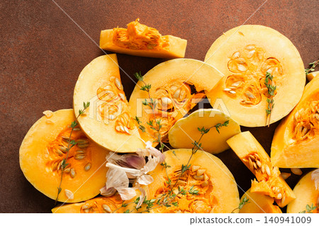Pumpkin slices are arranged on a kitchen counter with fresh herbs nearby. The scene shows the preparation of seasonal dishes in the fall Pumpkin slices are arranged on a kitchen counter with fresh herbs nearby. The scene shows the preparation of seasonal dishes in the fall 140941009