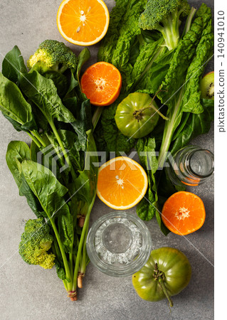 Fresh spinach, chard, and broccoli sit among sliced oranges and tangerines as juice is prepared in a kitchen. The scene captures a vibrant approach to healthy drinking Fresh spinach, chard, and broccoli sit among sliced oranges and tangerines as juice is prepared in a kitchen. The scene captures a vibrant approach to healthy drinking 140941010