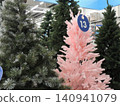 The store offers artificial Christmas trees. The pink one has a price tag with the number 13 attached. Pre-holiday sale on Christmas decor. 140941079