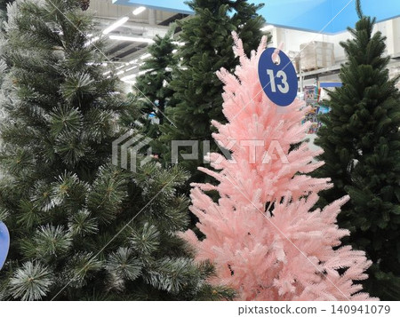 The store offers artificial Christmas trees. The pink one has a price tag with the number 13 attached. Pre-holiday sale on Christmas decor. The store offers artificial Christmas trees. The pink one has a price tag with the number 13 attached. Pre-holiday sale on Christmas decor. 140941079