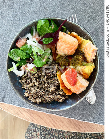 A quinoa bowl is filled with baked salmon, broccoli, tomatoes, and a fresh salad. This dish is good for breakfast or lunch and is rich in protein and nutrients A quinoa bowl is filled with baked salmon, broccoli, tomatoes, and a fresh salad. This dish is good for breakfast or lunch and is rich in protein and nutrients 140941790