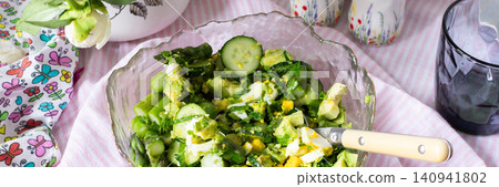 A bowl filled with cucumber salad features boiled eggs, asparagus, and avocado mixed with fresh greens. The salad is made from organic vegetables harvested in summer, banner A bowl filled with cucumber salad features boiled eggs, asparagus, and avocado mixed with fresh greens. The salad is made from organic vegetables harvested in summer, banner 140941802