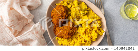 Enjoy a flavorful meal featuring rice topped with rhubarb fried eggs, baked sweet potato, and colorful veggies. Fresh salad and crispy meat fritters complete this delightful dish, banner 140941841